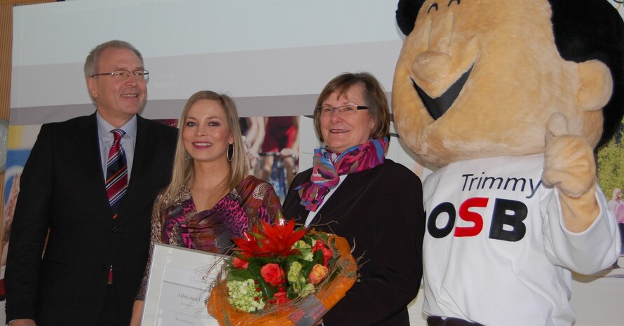 Michael Vesper, Ilse Ridder-Melchers und Trimmy verleihen Regina Halmich (mitte) die DOSB-Ehrennadel.