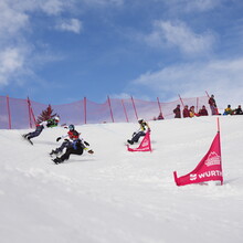 Snowboardfahrer*innen und Zuschauer*innen im Schnee bei blauem Himmel / Foto: Snowboard Germany