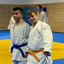 zwei etwa gleich große junge Männer in Judo-Anzügen schauen in die Kamera
