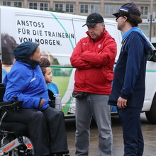 eine Gruppe von drei Personen vor einem Auto mit der Aufschrift: Anstoss für die Trainerin von morgen