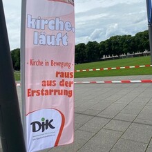 Eine Beach-Flag mit der Aufschrift: Kirche läuft - Raus aus der Erstarrung DJK