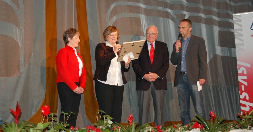 DOSB-Vizepräsidentin Ilse Ridder-Melchers (2. v.l.) überreicht LSV-Präsident Dr. Ekkehard Wienholtz und LSV-Vorstandsmitglied Sylvia Nowack die Siegerurkunde des DOSB. Ganz rechts Moderator Ralf Huber. (Foto: LSV SH)