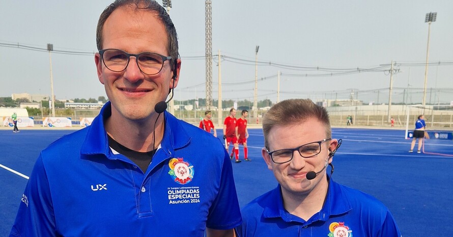 zwei Männer in blauen Shirts schauen in die Kamera