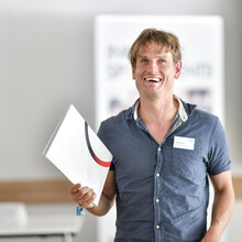 Das Gesicht eines lachenden, jungen Mannes mit kurzen blonden Haaren 