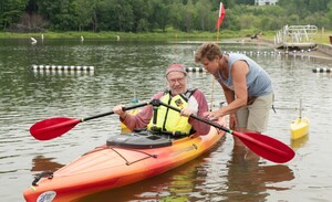 Eine Frau steht im Wasser und hilft einem Kanuten, der im Boot sitzt